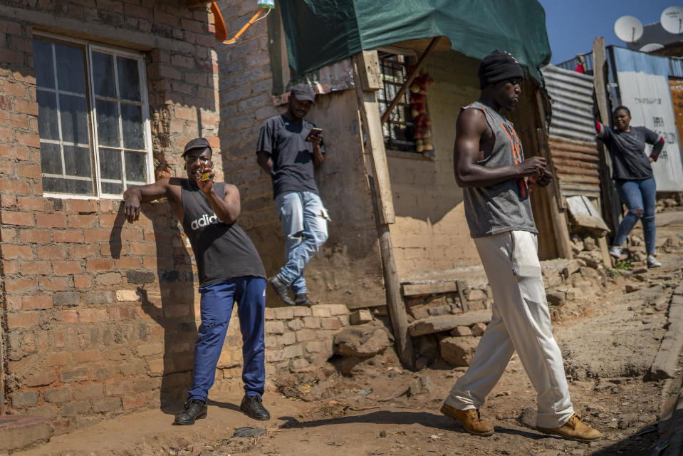 Residents of the Sjwetla informal settlement on the outskirt of the Alexandra township in Johannesburg stand outside their homes, Tuesday May 5, 2020. Up to 1600 South Africans living on the banks of the often flooding Jukskei river will be moved to less congested higher grounds in the coming months. South Africa begun a phased easing of its strict lockdown measures on May 1, and its confirmed cases of coronavirus continue to increase as more people are being tested. (AP Photo/Jerome Delay)