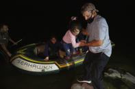 FILE - In this March 30, 2021, file photo, a little girl is helped off an inflatable raft by a church volunteer after being smuggled across the Rio Grande river in Roma, Texas. Roma, a town of 10,000 people with historic buildings and boarded-up storefronts in Texas' Rio Grande Valley, is the latest epicenter of illegal crossings, where growing numbers of families and children are entering the United States to seek asylum. U.S. officials are scrambling to handle a dramatic spike in children crossing the U.S.-Mexico border alone. (AP Photo/Dario Lopez-Mills, File)