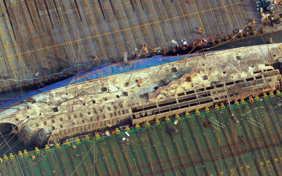 This aerial image shows part of the damaged Sewol ferry between two barges after being raised during a salvage operation at sea off the southwestern island of Jindo - Credit: AFP 