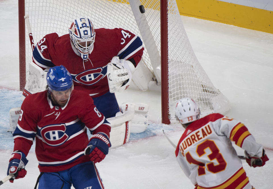 Calgary Flames' Johnny Gaudreau (13) scores against Montreal Canadiens goaltender Jake Allen, top, as Canadiens' Ben Chiarot (8) defends during first-period NHL hockey game action in Montreal, Saturday, Jan. 30, 2021. (Graham Hughes/The Canadian Press via AP)