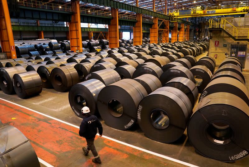 A worker walks past steel rolls at the ArcelorMittal steel plant in Sestao