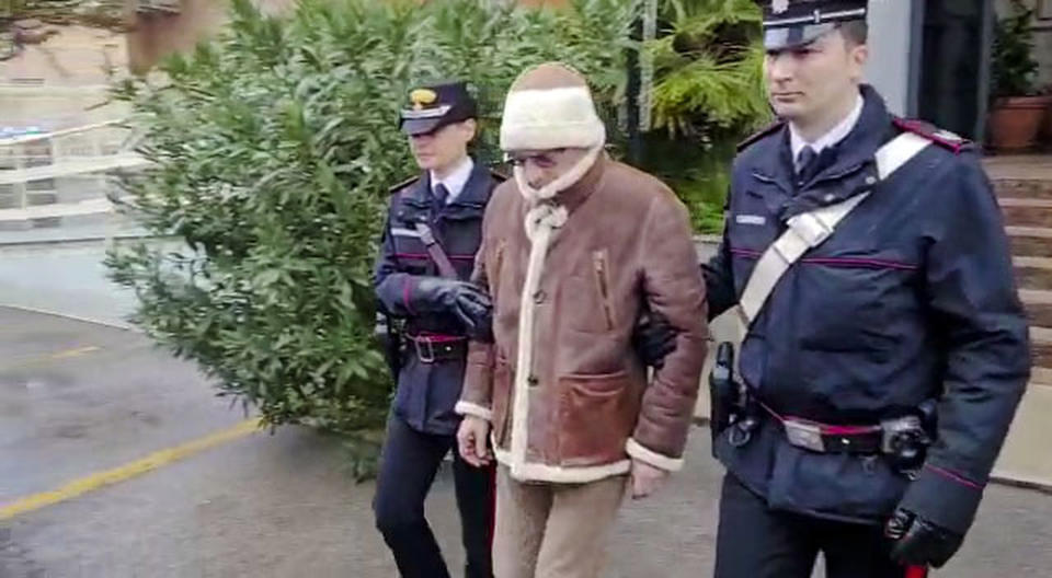 In this picture taken from a video released by Italian Carabinieri on Monday, Jan. 16, 2023, top Mafia boss Matteo Messina Denaro, center, leaves an Italian Carabinieri barrack soon after his arrest at a private clinic in Palermo, Sicily, after 30 years on the run, Monday, Jan. 16, 2023. (Carabinieri via AP)