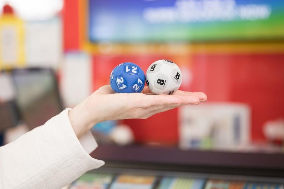 Hand holds out Powerball balls, numbered 21 and 8
