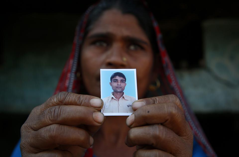 In this Wednesday, Feb. 12, 2014 photo, Taravati, who uses only one name, shows a photograph of her son Shiv Kumar Singh, a daily wage laborer, who was killed by a tiger at Maniawala, in northern India. The tiger that killed Singh on Jan. 10 has killed at least nine people so far traveling over 120 miles of villages, small towns and even a highway, spreading fear amongst the villagers many of whom are either farmers or laborers working the the large swathes of sugarcane fields which need harvesting now. (AP Photo/Saurabh Das)