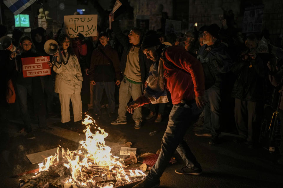 People burn torches after a march demanding the immediate release of the Israeli hostages held in the Gaza Strip by the Hamas militant group, in Jerusalem, Monday, Feb. 19, 2024. (AP Photo/Leo Correa)