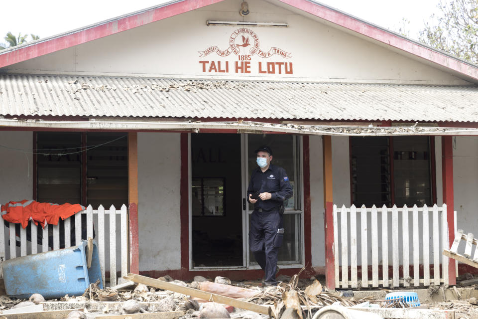 In this photo provided by the Australian Defence Force, an officer of Department of Foreign Affairs & Trade Crisis response team assesses damage to Atata island, in Nuku'alofa, Tonga, following the eruption of underwater volcano, on Feb. 4, 2022. (CPL Robert Whitmore/Australian Defence Force via AP)
