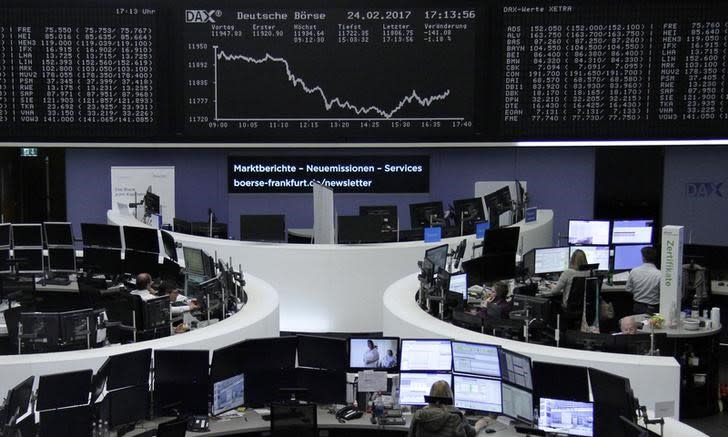 Traders work at their desks in front of the German share price index, DAX board, at the stock exchange in Frankfurt, Germany, February 24, 2017. REUTERS/Staff/Remote