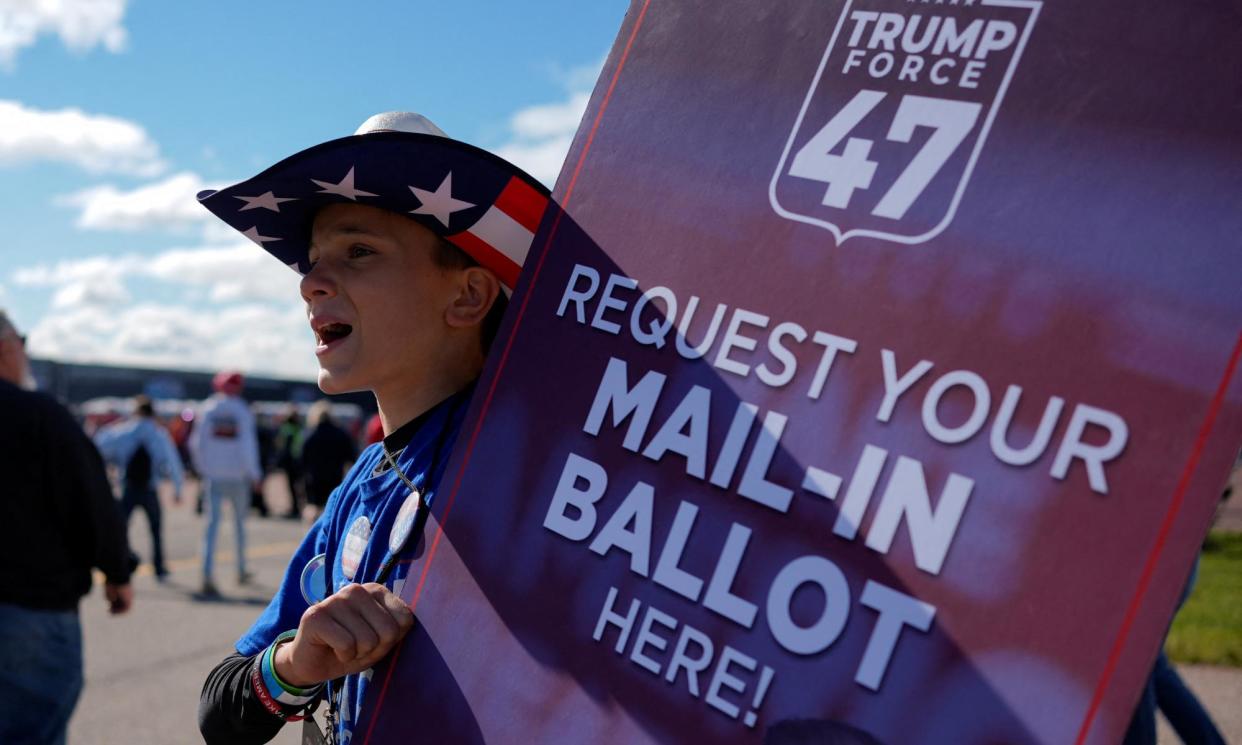 <span>A person holds a sign asking people to request their mail-in ballot, on the day of Trump's rally in Mosinee, Wisconsin, on 7 September 2024.</span><span>Photograph: Brian Snyder/Reuters</span>