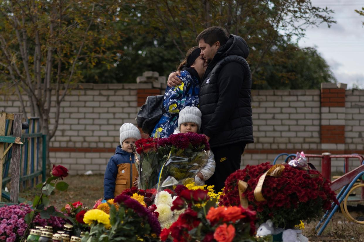 People react near the memorial for the victims of a Russian rocket attack in the village of Hroza (AP)