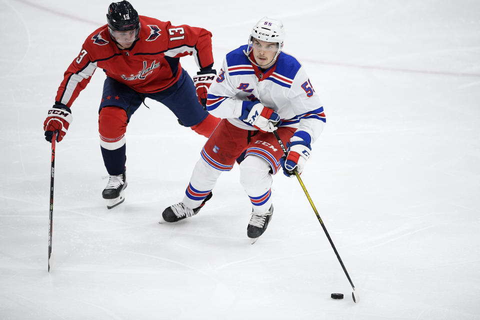 New York Rangers defenseman Ryan Lindgren (55) skates with the puck past Washington Capitals left wing Jakub Vrana (13) during the second period of an NHL hockey game, Sunday, March 28, 2021, in Washington. (AP Photo/Nick Wass)