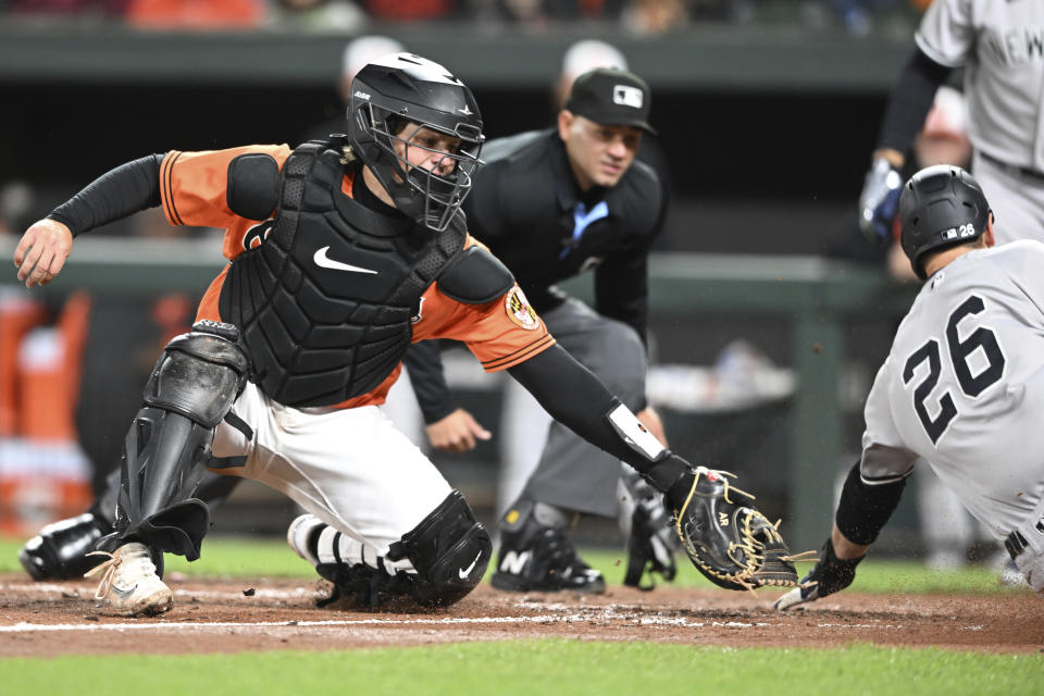 Baltimore Orioles catcher Adley Rutschmann reaches for New York Yankees' DJ LeMahieu as he slides safely across the plate to score in the fifth inning of a baseball game on Saturday, April 8, 2023, in Baltimore. (AP Photo/Gail Burton)