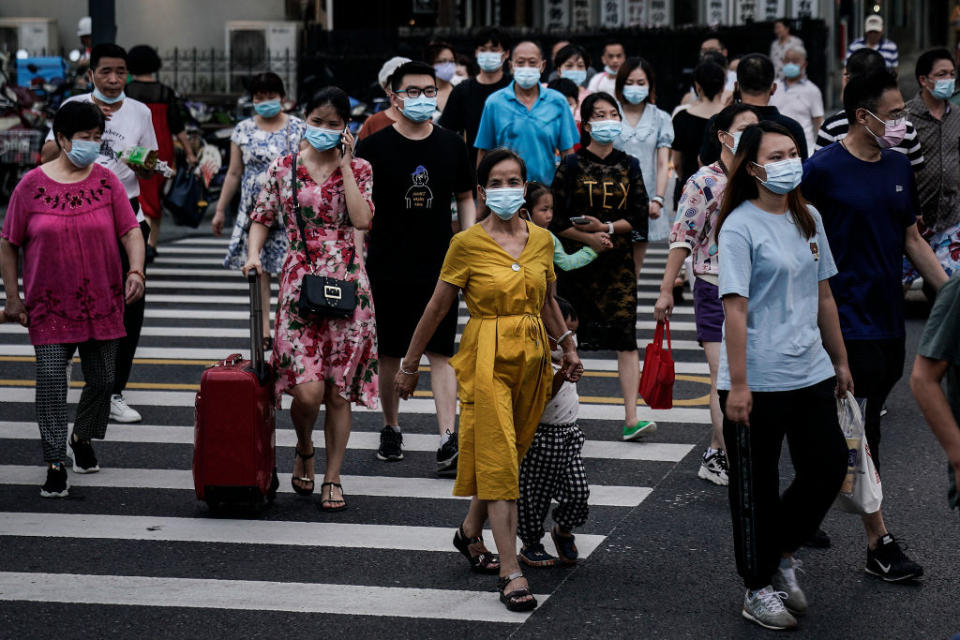 Masked Wuhan residents cross a pedestrian crossing.