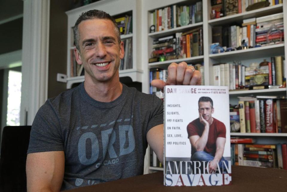 In this photo taken on May 22, 2013, author Dan Savage holds his new book, "American Savage," as he sits in his home in Seattle. Savage's latest book, "American Savage," was released on Tuesday, May 28. (AP Photo/Elaine Thompson)