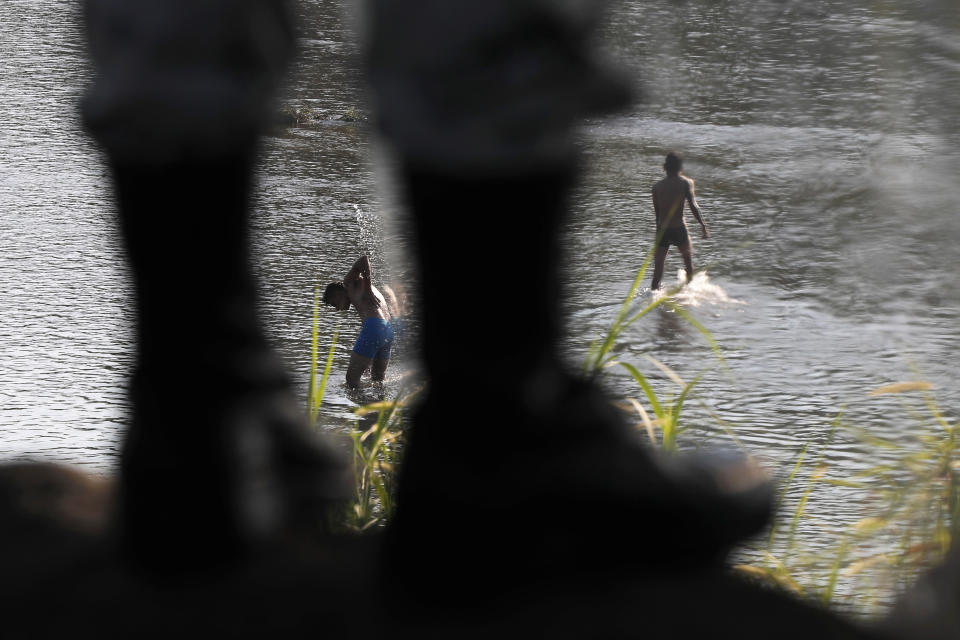 Two men walk in the Suchiate River as a Mexican National Guardsman stands on guard in Ciudad Hidalgo, on the Mexican border with Guatemala, Sunday, Jan. 19, 2020. Mexican authorities have closed a border entry point in southern Mexico after thousands of Central American migrants tried to push across a bridge between Mexico and Guatemala. (AP Photo / Marco Ugarte)