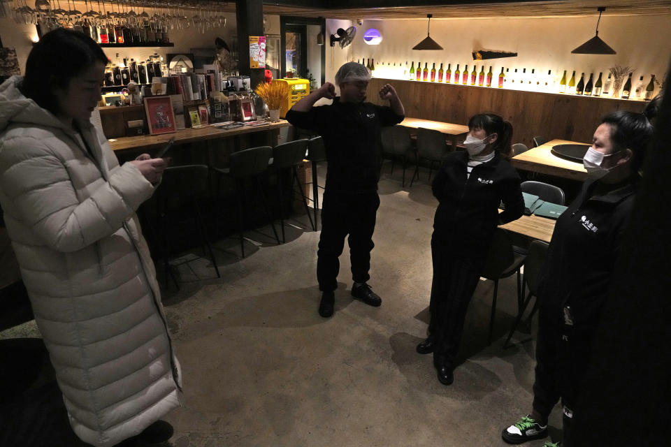 Workers are briefed before their shift at the Little Yunnan restaurant in Beijing, Wednesday, Dec. 28, 2022. After three years of quarantines pushed them close to shutting down, restaurant owner Li Meng and his wife are hoping for business to rebound after China rolled back severe anti-virus controls. But now they face a new challenge: Fear of its wave of infections is keeping diners away. (AP Photo/Ng Han Guan)