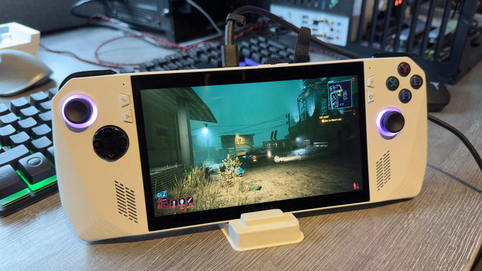 Photo of an Asus ROG Ally handheld gaming PC running Cyberpunk 2077 sitting in a white dock on a gray table