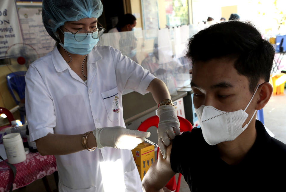 A Cambodian man, right, receives a shot of fourth dose of the Pfizer's COVID-19 vaccine at a heath center in Phnom Penh, Cambodia, Friday, Jan. 14, 2022. Cambodia on Friday began a fourth round of vaccinations against the coronavirus, following the recent discovery of cases of the omicron variant, with high-risk groups being the first to receive them. (AP Photo/Heng Sinith)
