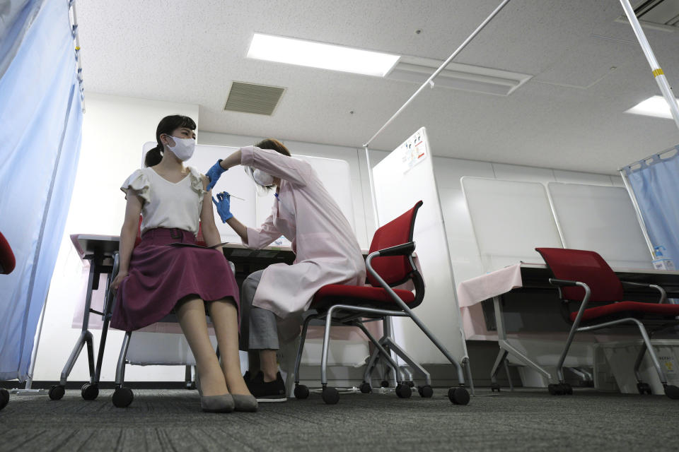 FILE - In this June 14, 2021, file photo, a flight attendant of Japan Airlines takes Moderna's COVID-19 vaccine shot at their office in Haneda Airport as the airline company began its workplace vaccination, in Tokyo. After months of delays due to political and bureaucratic bungling as well as a shortage of vaccines, inoculations in Japan are taking off, and the drive is now racing down to the wire with the Olympics starting in one month. (AP Photo/Eugene Hoshiko, File)