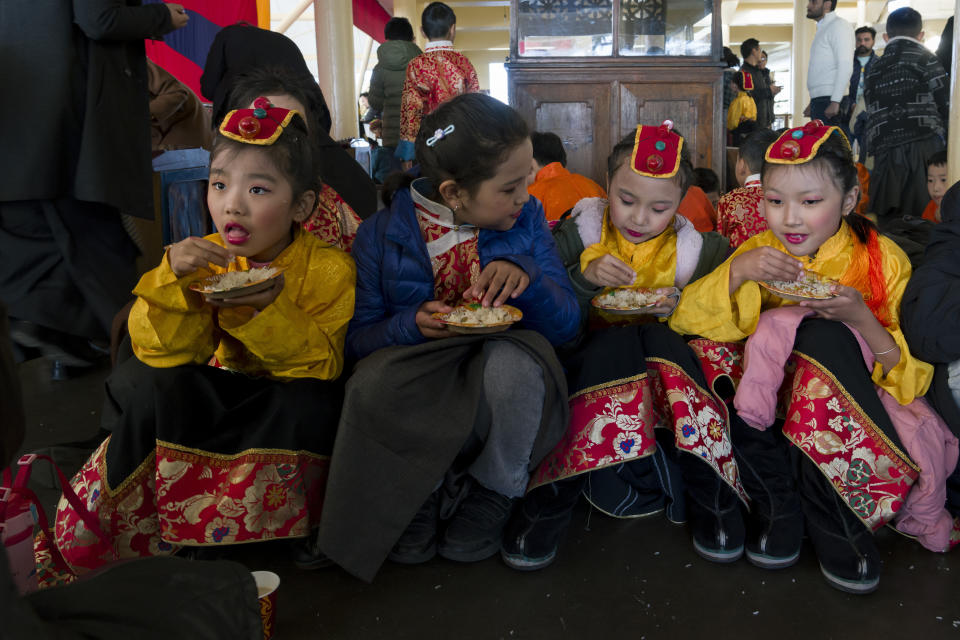 Exile Tibetan children in traditional costume eat sweetened rice at an event marking the anniversary of the awarding of the Nobel Peace Prize to the Dalai Lama in Dharamshala, India, Sunday, Dec. 10, 2023. (AP Photo/Ashwini Bhatia)