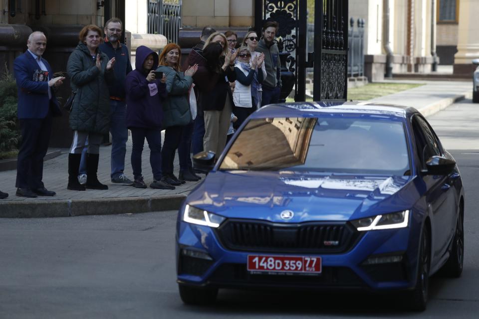 Embassy staff leave the Czech Republic Embassy by car as others applaud them, in Moscow, Russia, Monday, April 19, 2021. Russia has ordered 20 Czech diplomats to leave the country within a day in response to Prague's expulsion of 18 Russian diplomats. The Czech government has alleged the Russian Embassy staffers were spies for a military intelligence agency that was involved in a fatal ammunition depot explosion in 2014. (AP Photo/Pavel Golovkin)