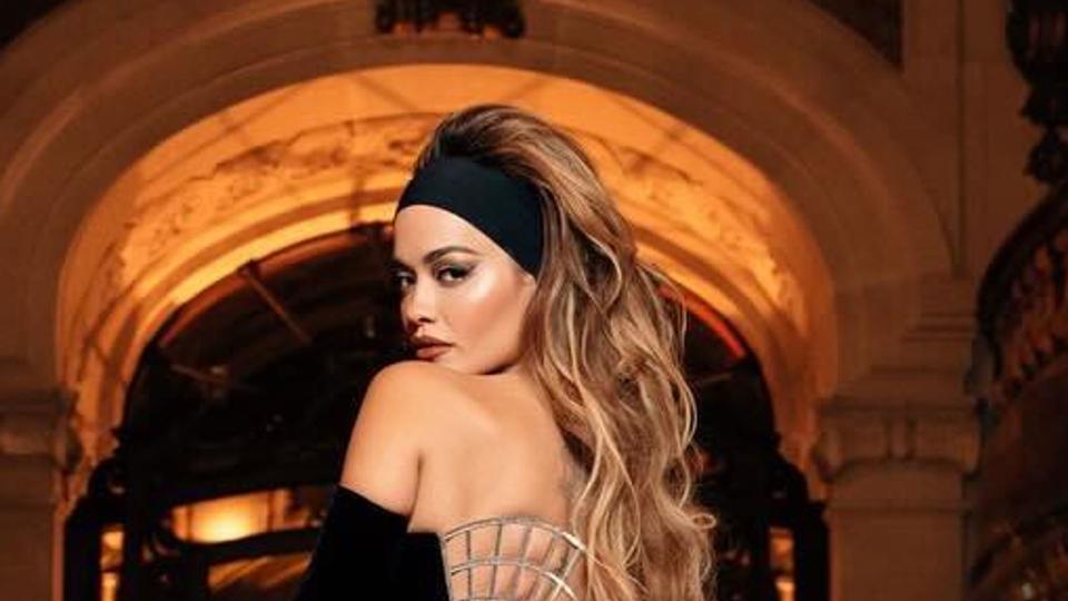 Rita Ora wears a thick black head band and gown at PFW 2024