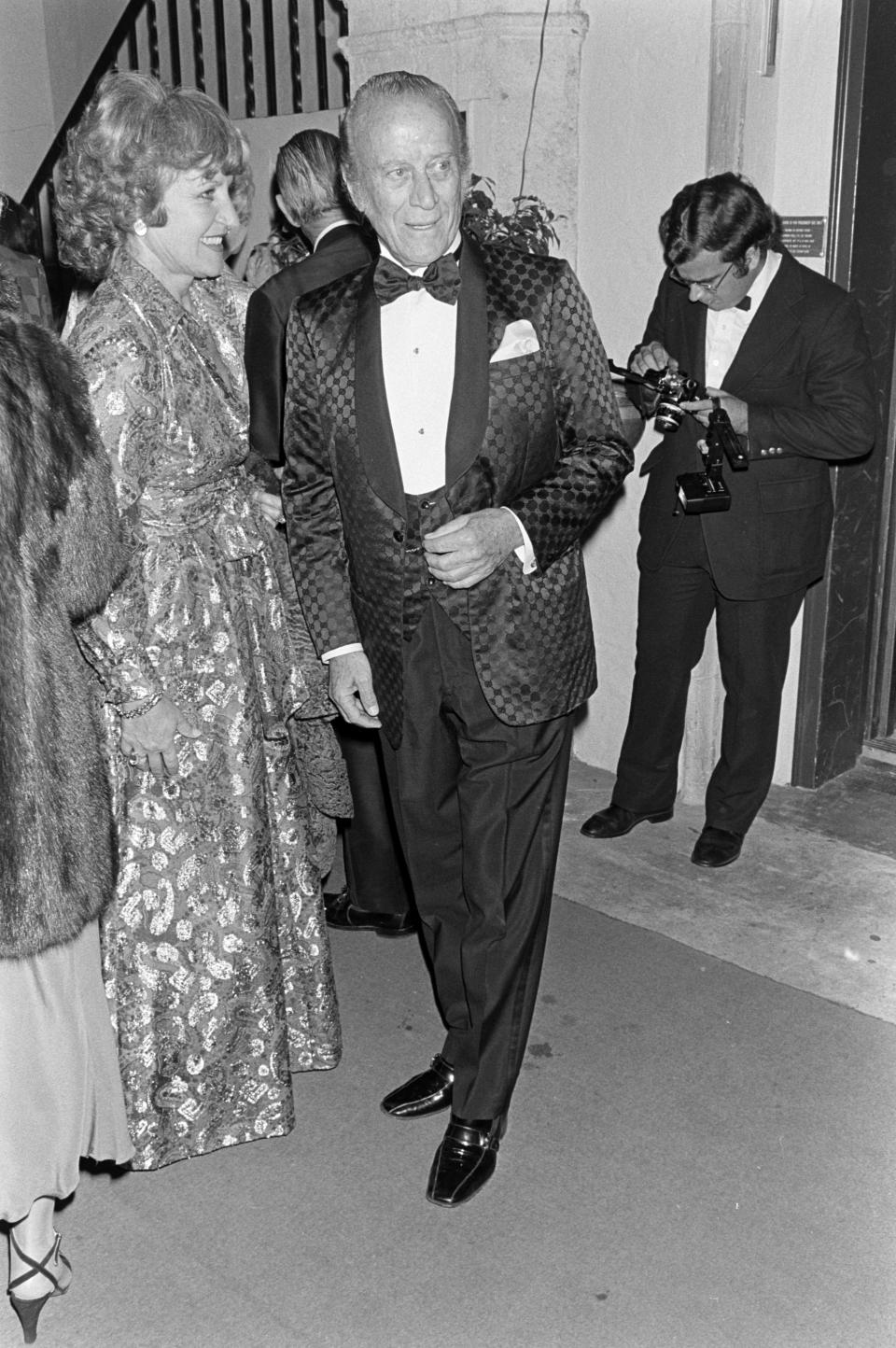 Aldo Gucci in a blue brocade Gucci evening coat greets guest during reception at his Palm Beach, Fla., home on Dec. 2, 1979. - Credit: WWD