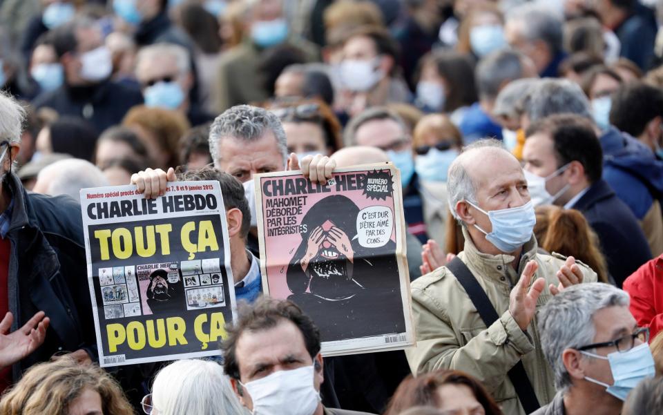 A man at a protest holding up copies of Charlie Hebdo with the controversial cartoons - Antoine Gyori/Corbis