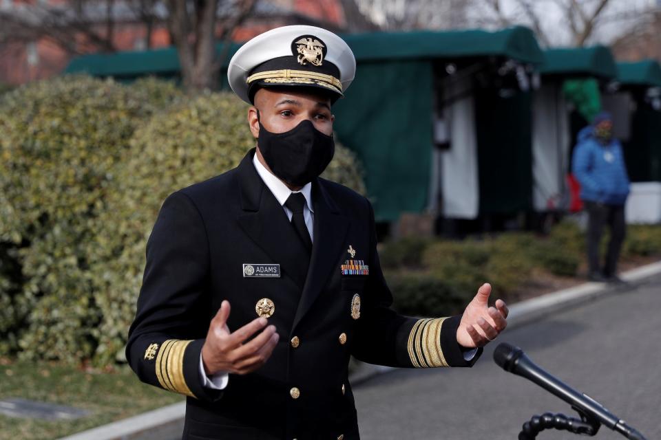 surgeon general jerome adams wearing military uniform and black face mask speaking outside in front of a microphone