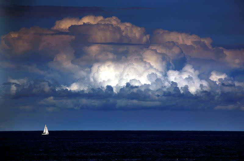 FILE PHOTO: A storm cloud can be seen behind a yacht as it sails off the coast of Sydney
