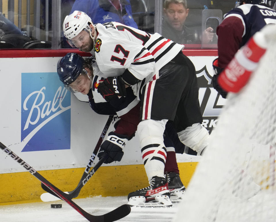 Chicago Blackhawks center Jason Dickinson, top, pins Colorado Avalanche defenseman Bowen Byram to the board during a fight for control of the puck in the second period of an NHL hockey game Monday, March 20, 2023, in Denver. (AP Photo/David Zalubowski)