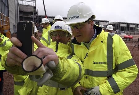 Britain's Prime Minister David Cameron (R) poses for a selfie photograph with a worker as he visits the Longbridge redevelopment site in Birmingham, Britain April 29, 2015. REUTERS/Carl Court/pool