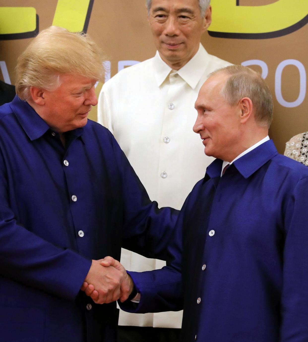 US President Donald Trump (L) shakes hands with Russia's President Vladimir Putin (R) as they pose for a group photo ahead of the Asia-Pacific Economic Cooperation (APEC) Summit leaders gala dinner in the central Vietnamese city of Danang on November 10, 2017. / AFP PHOTO / SPUTNIK / Mikhail KLIMENTYEVMIKHAIL KLIMENTYEV/AFP/Getty Images