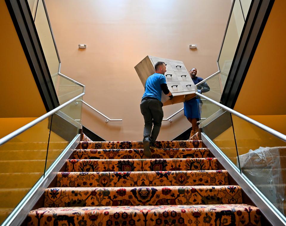 Warehouse manager Luis Baez, left, of Clinton and delivery driver Prentice Jones of Worcester carry a dresser to the second floor of Harte's Home in Auburn.