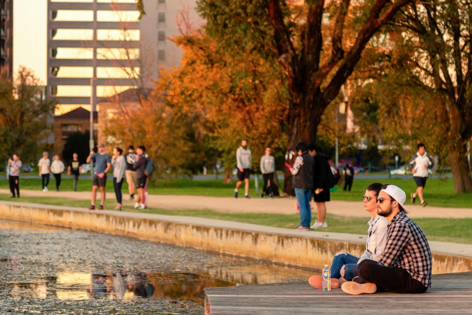 A couple sits by the edge of Albert Park Lake to watch the sunset as restrictions are being eased in Victoria.