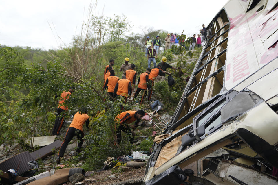 Jammu & Kashmir State Disaster Response Force (SDRF) personnel inspect the wreckage after a bus carrying Hindu pilgrims to a shrine skid off a highway bridge into a Himalayan gorge near Jammu, India, Tuesday, May 30, 2023. (AP Photo/Channi Anand)