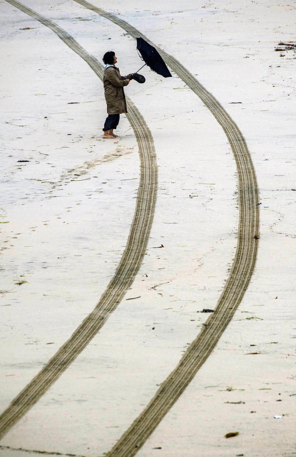 The strong wind catches a woman's umbrella as she walks along the beach just north of the Huntington Beach Pier in Huntington Beach on Thursday morning, Jan. 17, 2019, as another storm brought more rain to Orange County and Southern California. (Mark Rightmire/Orange County Register via AP)