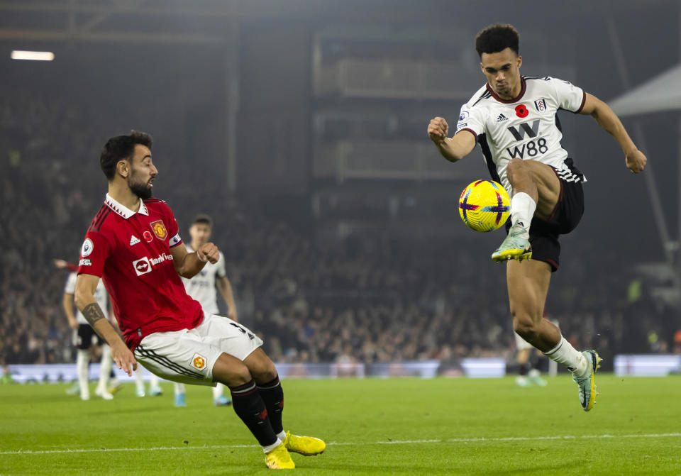 Fulham's Antonee Robinson, right, duels for the ball with Manchester United's Bruno Fernandes during the English Premier League soccer match between Fulham and Manchester United at the Craven Cottage stadium in London, Sunday, Nov. 13, 2022. (AP Photo/Leila Coker)