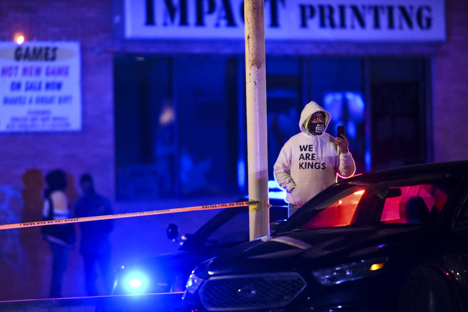 A man takes a video using his cell phone as the Bureau of Criminal Apprehension investigate the scene where St. Paul Police shot a man multiple times earlier in the night after responding to a domestic assault report near the intersection of Rice Street and Magnolia Ave., on Sunday, Nov. 29, 2020, in St. Paul, Minn. (Aaron Lavinsky/Star Tribune via AP)