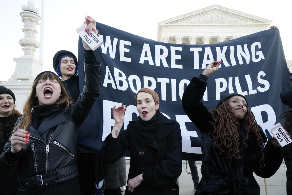 Amelia Bonow, left, Erin Jorgensen, center, and Alana Edmondson, right, show and then take abortion pills to make a statement about how safe and available they believe they are, as they demonstrate in front of the U.S. Supreme Court Wednesday, Dec. 1, 2021, in Washington. The court will hear arguments in a case from Mississippi, where a 2018 law would ban abortions after 15 weeks of pregnancy, well before viability. (AP Photo/Jacquelyn Martin)