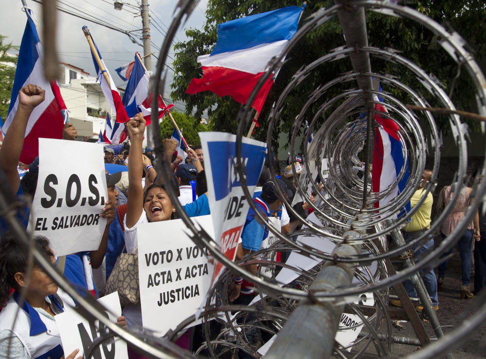 Supporters of Norman Quijano, Nationalist Republican Alliance presidential candidate protest in front of a barricade set up by police, demanding a vote recount of Sunday's runoff election, in San Salvador, El Salvador, Tuesday, March 11, 2014. El Salvador's too-close-to-call election has raised competing claims of victory from the two candidates; Salvador Sanchez Ceren of the Farabundo Marti National Liberation Front and Quijano. (AP Photo/Esteban Felix)