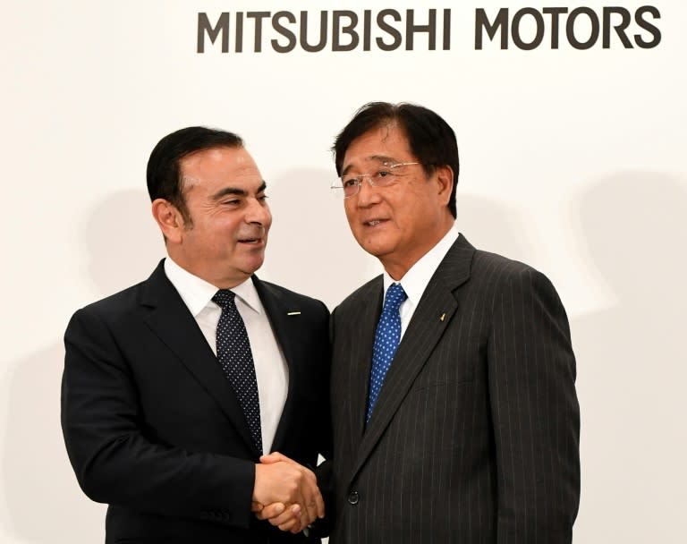 Nissan Motors chairman and CEO Carlos Ghosn chats with Mitsubishi Motors president and CEO Osamu Masuko (right) during a photo session in Tokyo on October 20, 2016