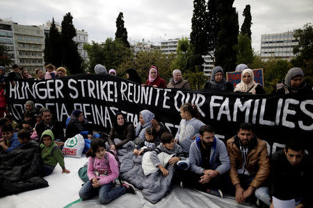 Refugees seeking reunification with family members in Germany sit in front of a banner announcing a hunger strike during a protest near the parliament building in Athens, Greece, November 1, 2017. REUTERS/Alkis Konstantinidis