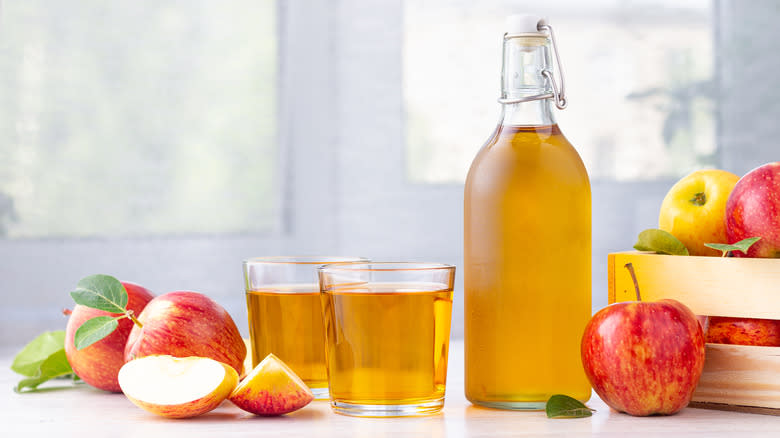 apple cider and red apples on table