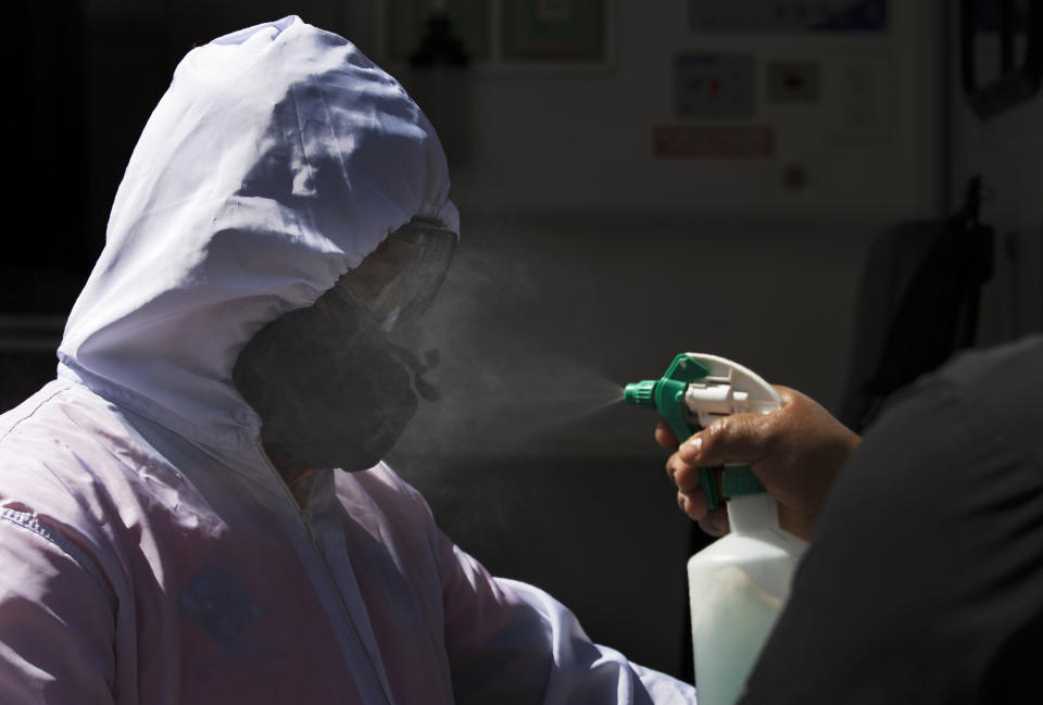 Paramedics Carolina Estrada, left, is disinfected by her partner Elvin Munguia after mobilizing a COVID-19 patient from his home to a hospital in the Iztapalapa district of Mexico City, Tuesday, Feb. 2, 2021. (AP Photo/Marco Ugarte)