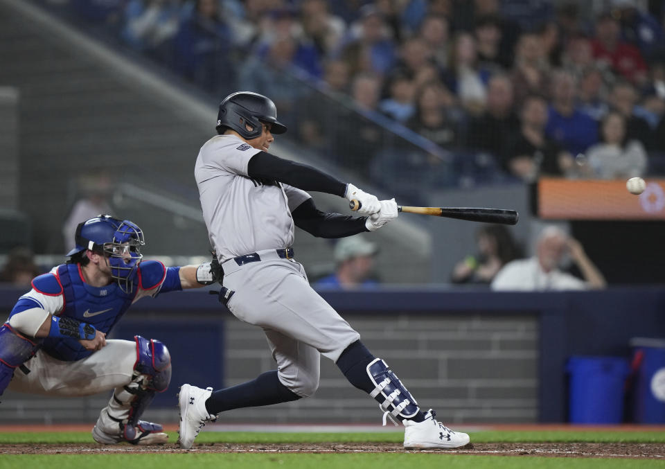 New York Yankees' Juan Soto hits a single next to Toronto Blue Jays catcher Danny Jansen during the sixth inning of a baseball game Tuesday, April 16, 2024, in Toronto. (Nathan Denette/The Canadian Press via AP)