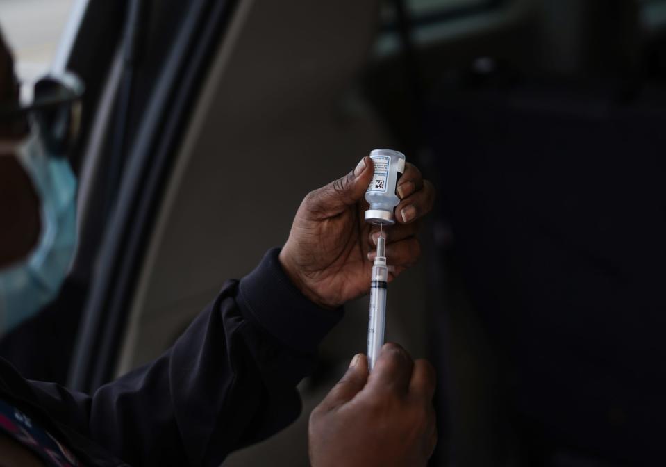 Central City Integrated Health RN Precious McCormick draws up a dose of the Moderna COVID-19 vaccine to be given to a person along Hamilton Avenue in Detroit on Wednesday, April 28, 2021. Central City Integrated Health paired up with The Salvation Army during their Bed & Bread Club delivery route as they deliver meals to those in need to help Detroit residents who might not have transportation to access the COVID vaccine.