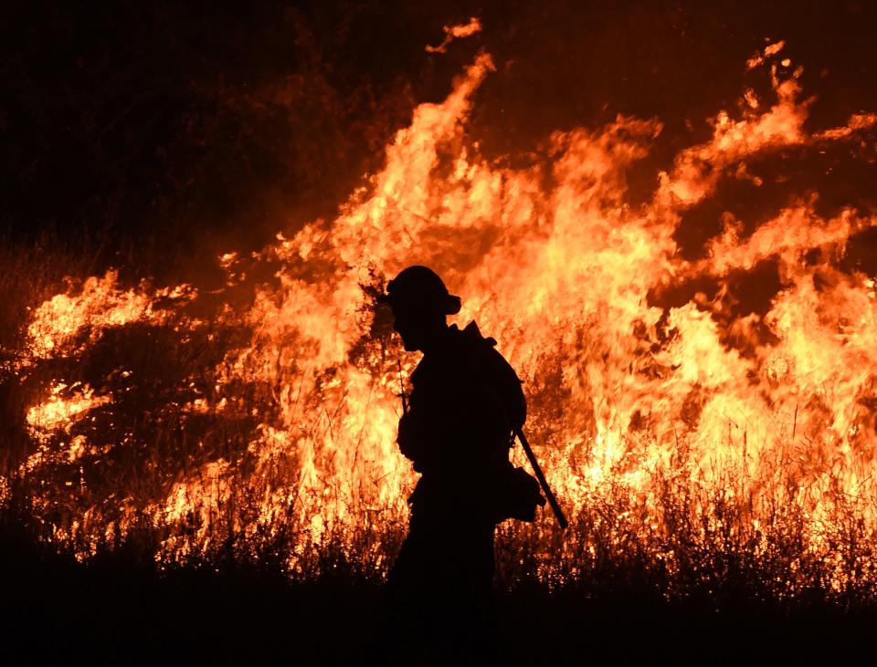 Firefighters conduct a controlled burn to defend houses against flames from the Ranch Fire.