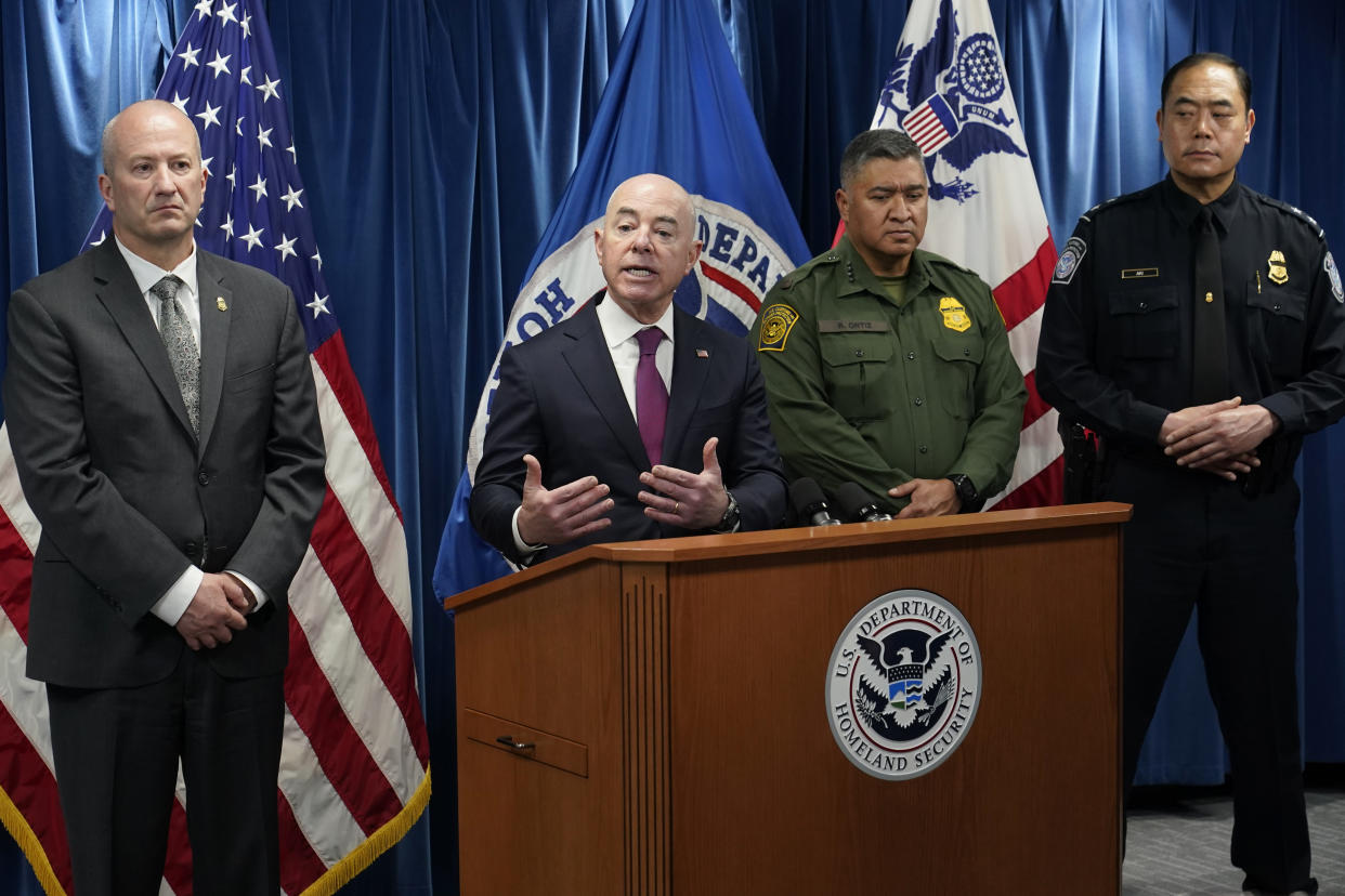 Alejandro Mayorkas at the microphone, with, from left, Troy Miller, wearing a suit, Raul Ortiz and Sidney Aki, both wearing uniforms.