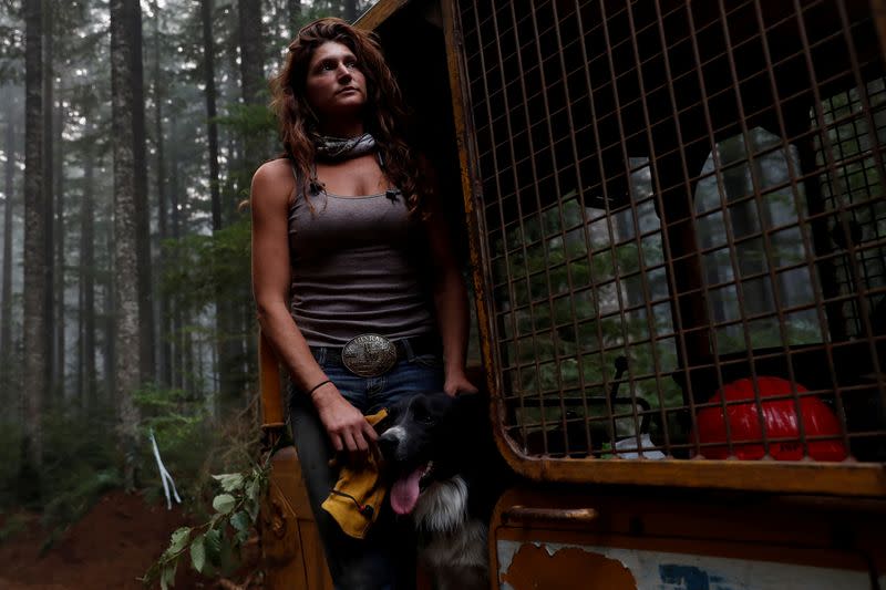 Nicole West, part of the Hillbilly Brigade of some 1,200 men and women who spontaneously came together to fight fires, stands for a portrait petting her dog Oink on a bulldozer during the aftermath of the Riverside Fire near Molalla, Oregon