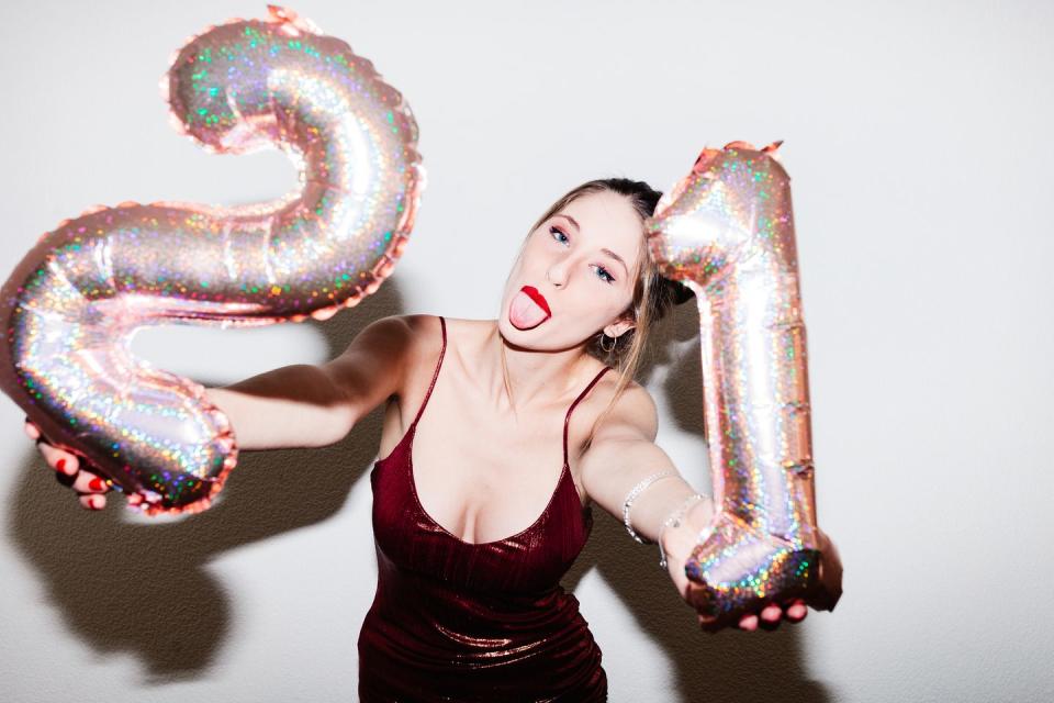 young woman celebrating her 21st birthday illuminated with hard flash light